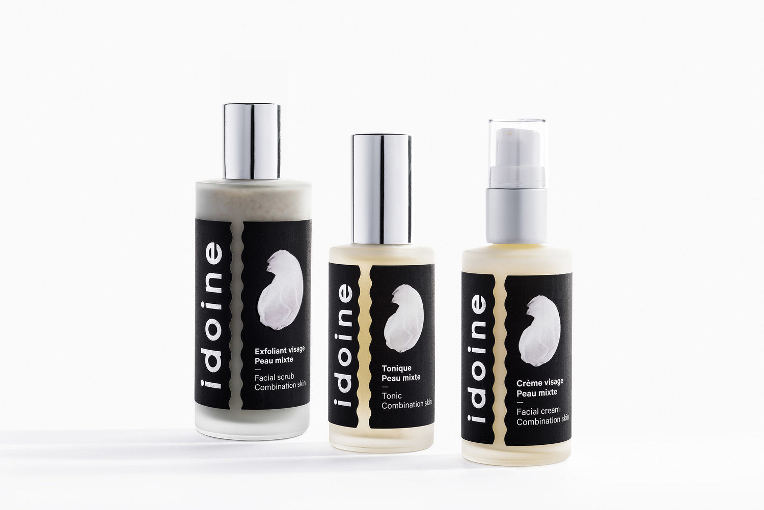 Une gamme de produits "Idoine" pour peau mixte : exfoliant, tonique et crème, sur fond blanc, avec étiquettes noires et blanches.
